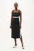 Woman wearing a black sleeveless midi dress with white contrast trim, square neck, and side slit from Joseph Ribkoff