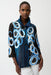 Woman wearing a black multi abstract print jacket with bell sleeves and button front, styled with white pants.