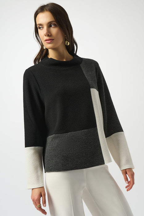 Woman wearing a black, gray, and white color-blocked sweater from Joseph Ribkoff