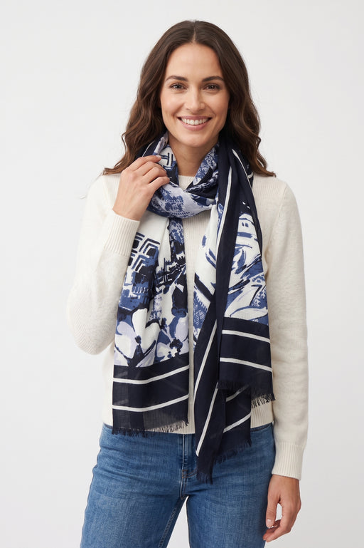 Woman wearing a blue floral and abstract patterned scarf with fringe edges from Joseph Ribkoff