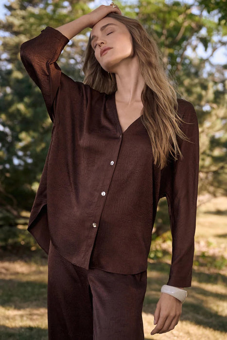 Woman wearing a brown Joseph Ribkoff boxy top with dolman sleeves, featuring a relaxed fit, button-front design, soft textured fabric, and an elegant modern silhouette.
