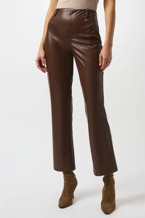 Woman wearing a solid color brown leatherette pant with belt loops and ornament