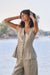 Woman wearing Joseph Ribkoff foiled linen peplum vest styled for summer events, resort wear, coordinated sets, and elegant casual outfits.