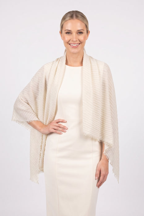 Woman wearing a beige pleated shawl with fringe edges from Joseph Ribkoff