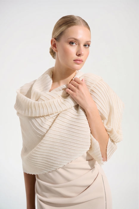 Woman wearing a cream-colored knit shrug over a dress against a white background