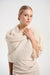 Woman wearing a cream-colored knit shrug over a dress against a white background