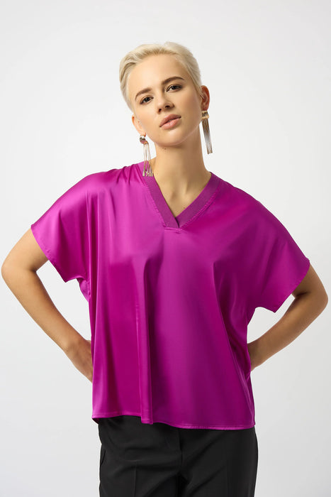 Woman wearing a purple satin top with v-neck and short sleeves