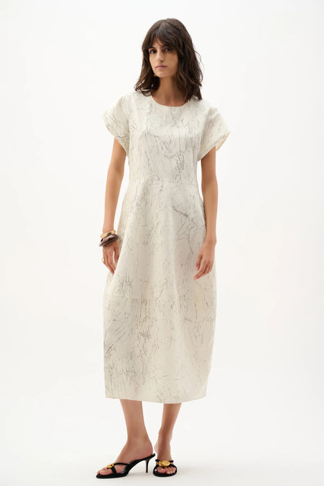 Woman wearing a Joseph Ribkoff abstract cocoon dress with dolman sleeves and sculptural silhouette, styled for modern chic events, travel, or elegant casual occasions.