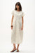 Woman wearing a Joseph Ribkoff abstract cocoon dress with dolman sleeves and sculptural silhouette, styled for modern chic events, travel, or elegant casual occasions.