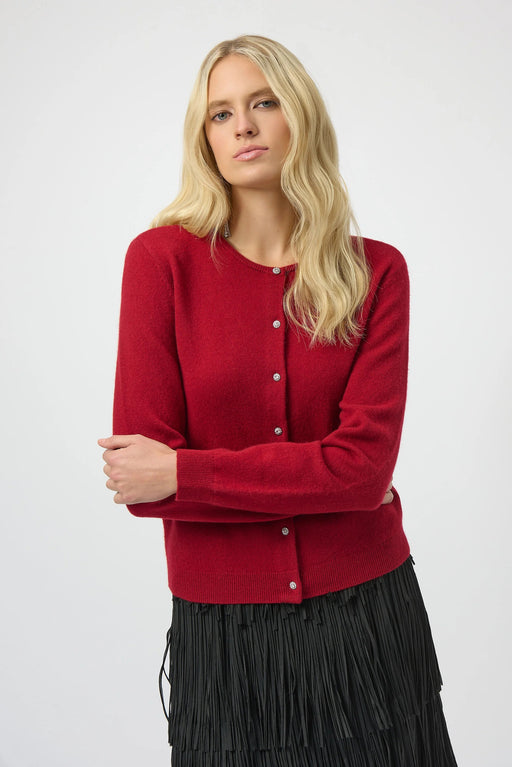 Woman wearing a red cashmere cardigan with rhinestone button front and long sleeves from Joseph Ribkoff