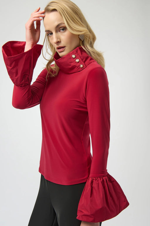 Woman wearing a red long-sleeve top with flounce cuffs and funnel neckline