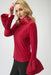 Woman wearing a red long-sleeve top with flounce cuffs and funnel neckline