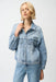 Woman wearing a light blue denim jacket with pearl and stud embellishments from Joseph Ribkoff