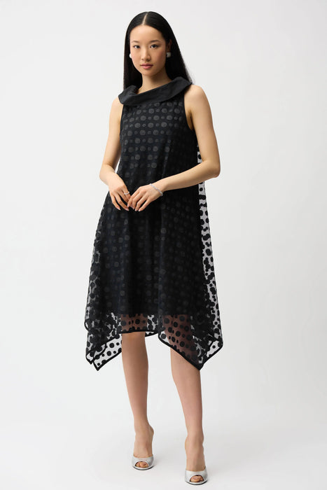 Woman wearing Joseph Ribkoff dot embroidered mesh handkerchief dress in black and midnight blue with sleeveless design and flowy asymmetrical hem.