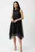 Woman wearing Joseph Ribkoff dot embroidered mesh handkerchief dress in black and midnight blue with sleeveless design and flowy asymmetrical hem.