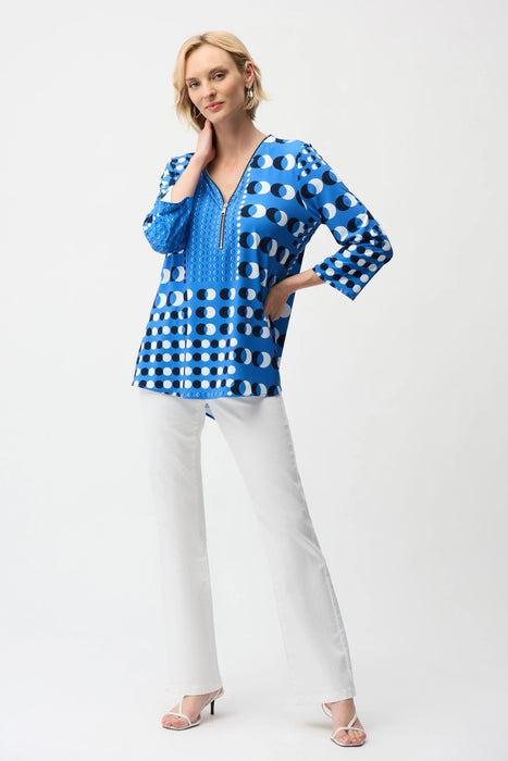 Woman wearing Joseph Ribkoff dot print fit and flare tunic with zipper, featuring a bold blue pattern, flowy silhouette, and stylish three-quarter sleeves.