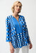 Woman wearing Joseph Ribkoff dot print fit and flare tunic with zipper, featuring a bold blue pattern, flowy silhouette, and stylish three-quarter sleeves.