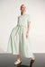Woman wearing a fit and flare waist midi dress with drawstring detail styled for a modern elegant and relaxed look