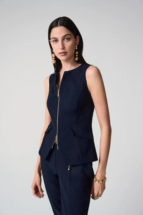 Woman wearing a fitted sleeveless vest with front zipper and tailored silhouette, paired with matching trousers.