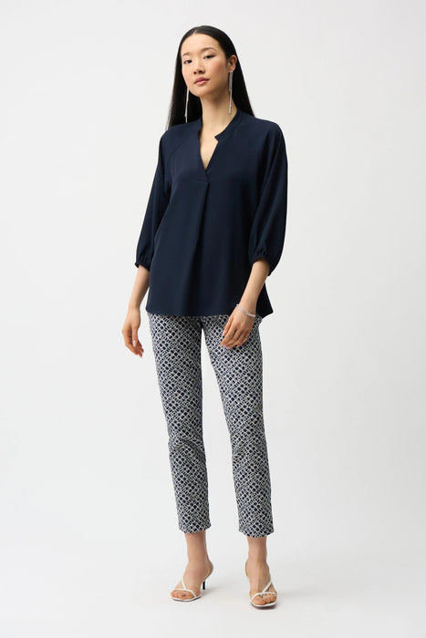 Woman wearing Joseph Ribkoff geometric print pull-on slim fit pants, featuring a modern patterned design, cropped length, and flattering stretch fit for chic styling.