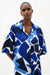 Woman wearing Joseph Ribkoff blue and white geometric print straight blouse, featuring a bold patterned design, relaxed silhouette, lightweight fabric, and a polished modern fit.