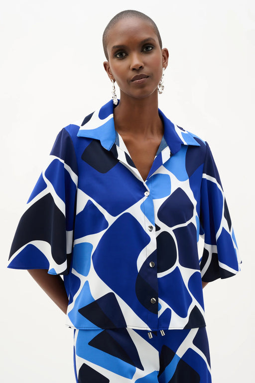 Woman wearing Joseph Ribkoff blue and white geometric print straight blouse, featuring a bold patterned design, relaxed silhouette, lightweight fabric, and a polished modern fit.