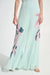 Woman wearing Joseph Ribkoff green/multi floral chiffon wide-leg pleated pants styled for resort vacation, summer events, evening dinners, and formal occasions.