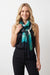 Woman wearing a green geometric patterned scarf with fringe edges from Joseph Ribkoff
