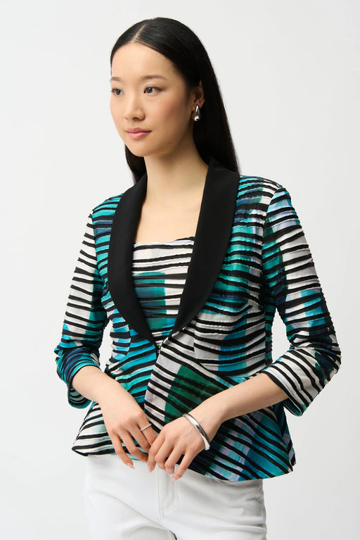 Woman wearing a green multi geometric print camisole with matching open-front jacket featuring a shawl collar, styled with white pants.