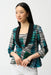 Woman wearing a green multi geometric print camisole with matching open-front jacket featuring a shawl collar, styled with white pants.