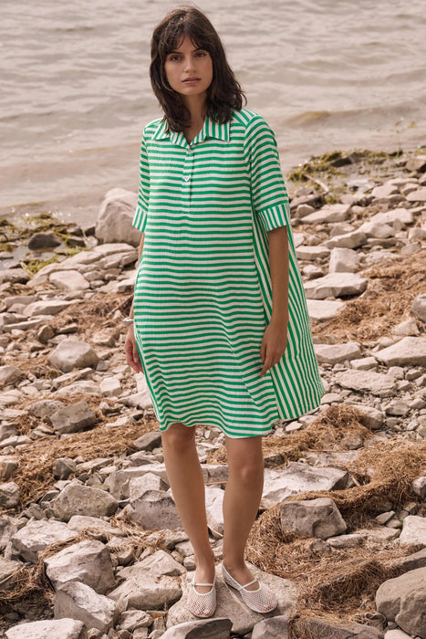 Woman wearing a green and vanilla striped trapeze dress with short sleeves and collared neckline, styled for a casual chic look