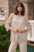 Woman wearing a neutral-toned guipure lace straight cover-up with floral detailing, styled over a matching top and pants.