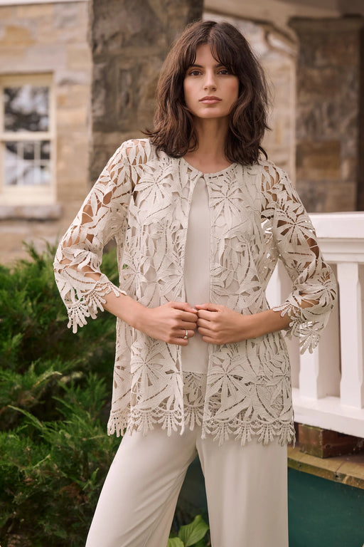 Woman wearing a neutral-toned guipure lace straight cover-up with floral detailing, styled over a matching top and pants.