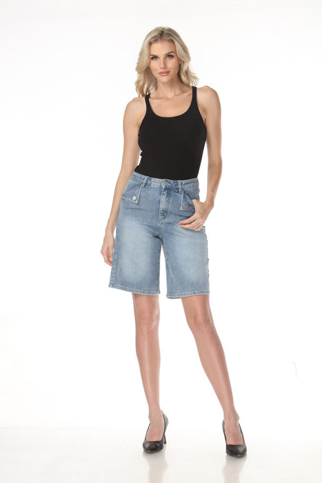 A woman posing in light-wash denim shorts and a black tank top against a plain white background.