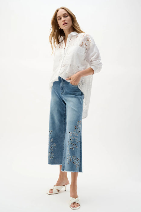 Woman wearing Joseph Ribkoff embroidery wide leg crop jeans, featuring light-wash denim, floral cutout embroidery, cropped length, and a relaxed modern fit.