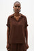 Woman wearing a brown short sleeves top with collared v-neck from Joseph Ribkoff