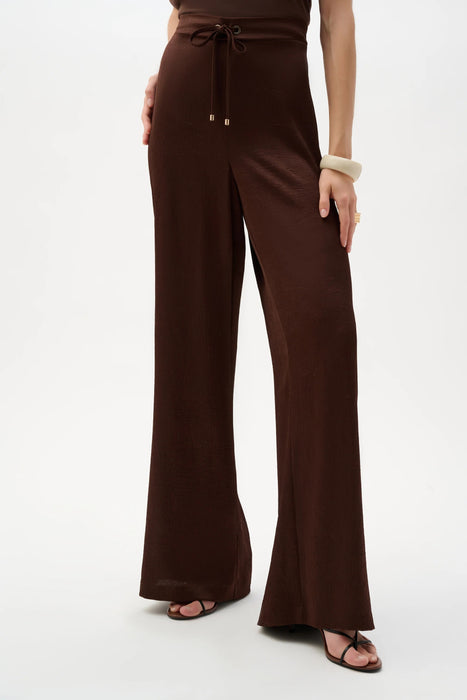 Woman wearing Joseph Ribkoff drawstring wide leg satin pants for elegant resort outfit