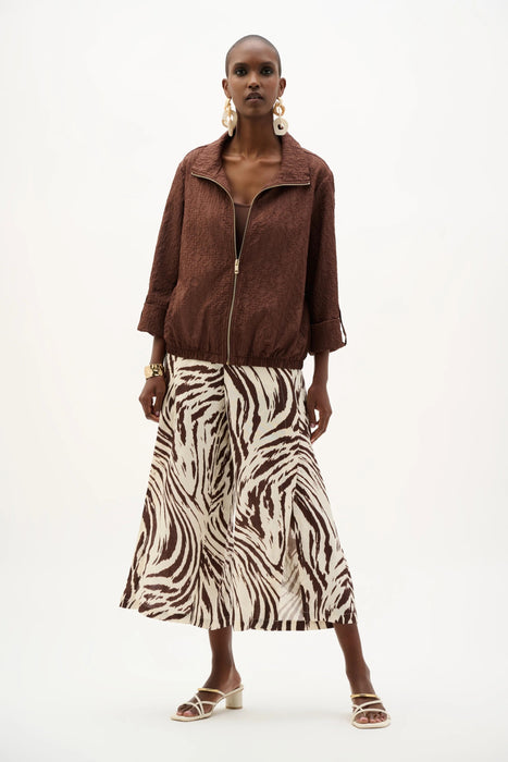 Woman wearing a mahogany funnel collar bomber jacket with a zip-up front and textured fabric, styled with rolled sleeves for a modern chic look.