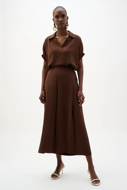 Woman wearing a brown Joseph Ribkoff pull-on culotte pants with pleats, featuring flowy wide-leg silhouette, cropped length, and a flattering high-rise modern fit.
