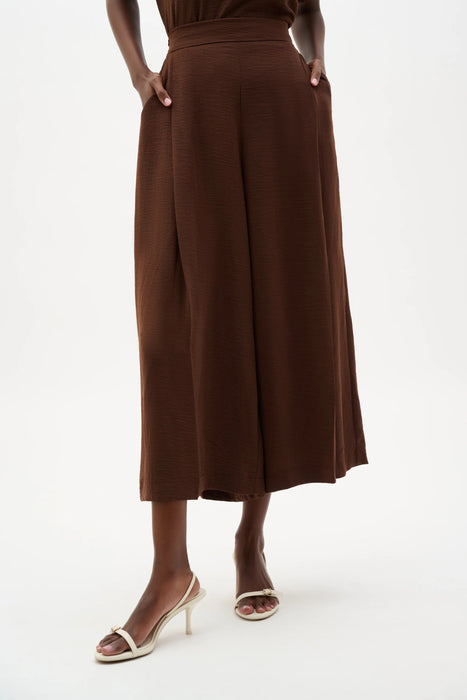 Woman wearing a brown Joseph Ribkoff pull-on culotte pants with pleats, featuring flowy wide-leg silhouette, cropped length, and a flattering high-rise modern fit.