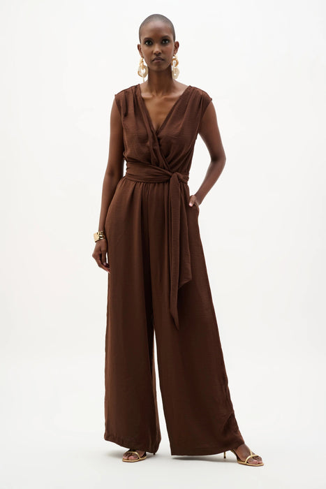 Woman wearing Joseph Ribkoff wide leg pull-on jumpsuit, featuring a flowy silhouette, relaxed fit, and elegant draped fabric for a chic one-piece look.