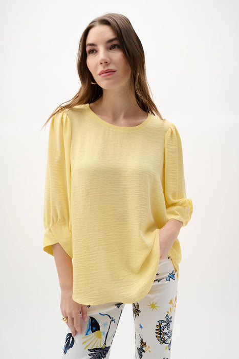 Woman wearing Joseph Ribkoff puff sleeves trapeze top, featuring a flowy silhouette, voluminous sleeves, lightweight fabric, and an elegant, modern fit.