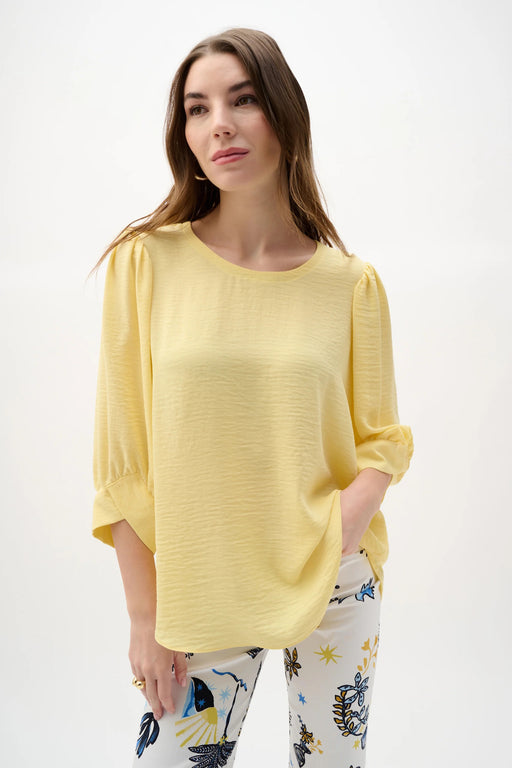 Woman wearing Joseph Ribkoff puff sleeves trapeze top, featuring a flowy silhouette, voluminous sleeves, lightweight fabric, and an elegant, modern fit.