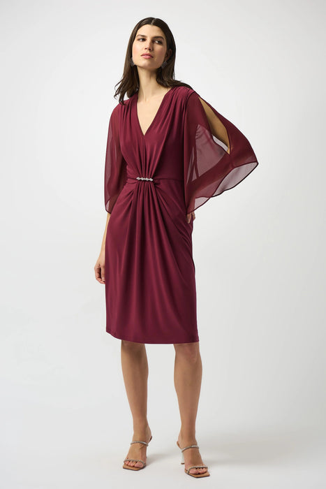 Woman wearing a burgundy sheath dress with ruching at the front and sheer chiffon slit sleeves