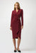 Woman wearing a burgundy knee length sheath dress with a buckle detail and wrap v-neck