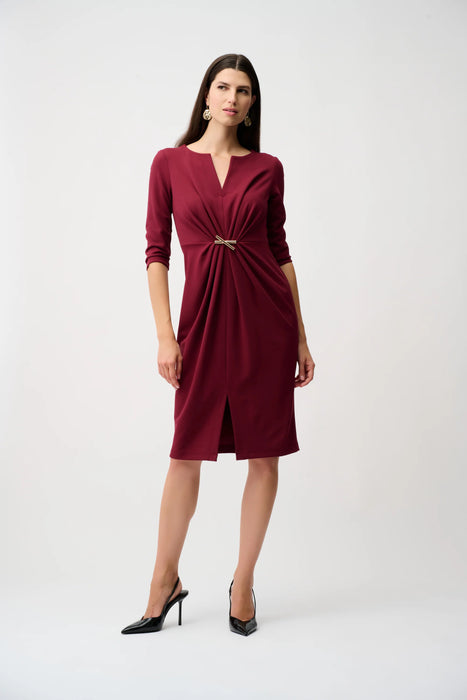 Woman wearing a burgundy sheath dress with ruching and ornament at the waist