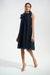 Woman wearing Joseph Ribkoff blue mesh and lace A-line dress with organza flower detail, featuring a pleated sheer overlay, sleeveless design, and elegant flowy silhouette.