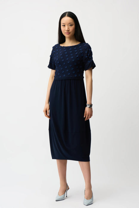 Woman wearing Joseph Ribkoff midnight blue 3D dot jacquard cocoon dress, featuring textured fabric, short sleeves, and a relaxed elegant midi silhouette.