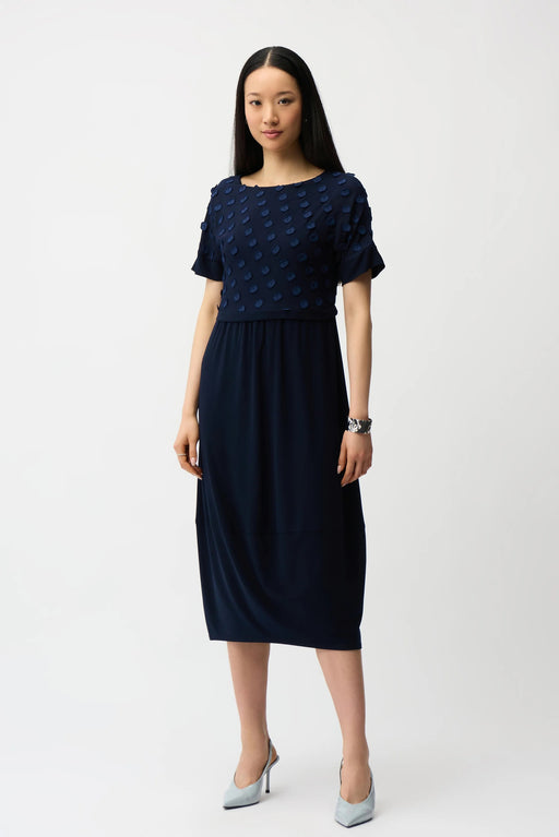Woman wearing Joseph Ribkoff midnight blue 3D dot jacquard cocoon dress, featuring textured fabric, short sleeves, and a relaxed elegant midi silhouette.