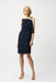 Woman wearing Joseph Ribkoff midnight blue asymmetrical neckline shift dress with draped detailing and shoulder accent, creating a modern elegant silhouette.